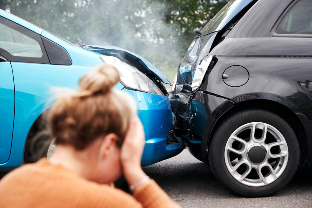 female motorist with head in hands sitting next to a rear end accident