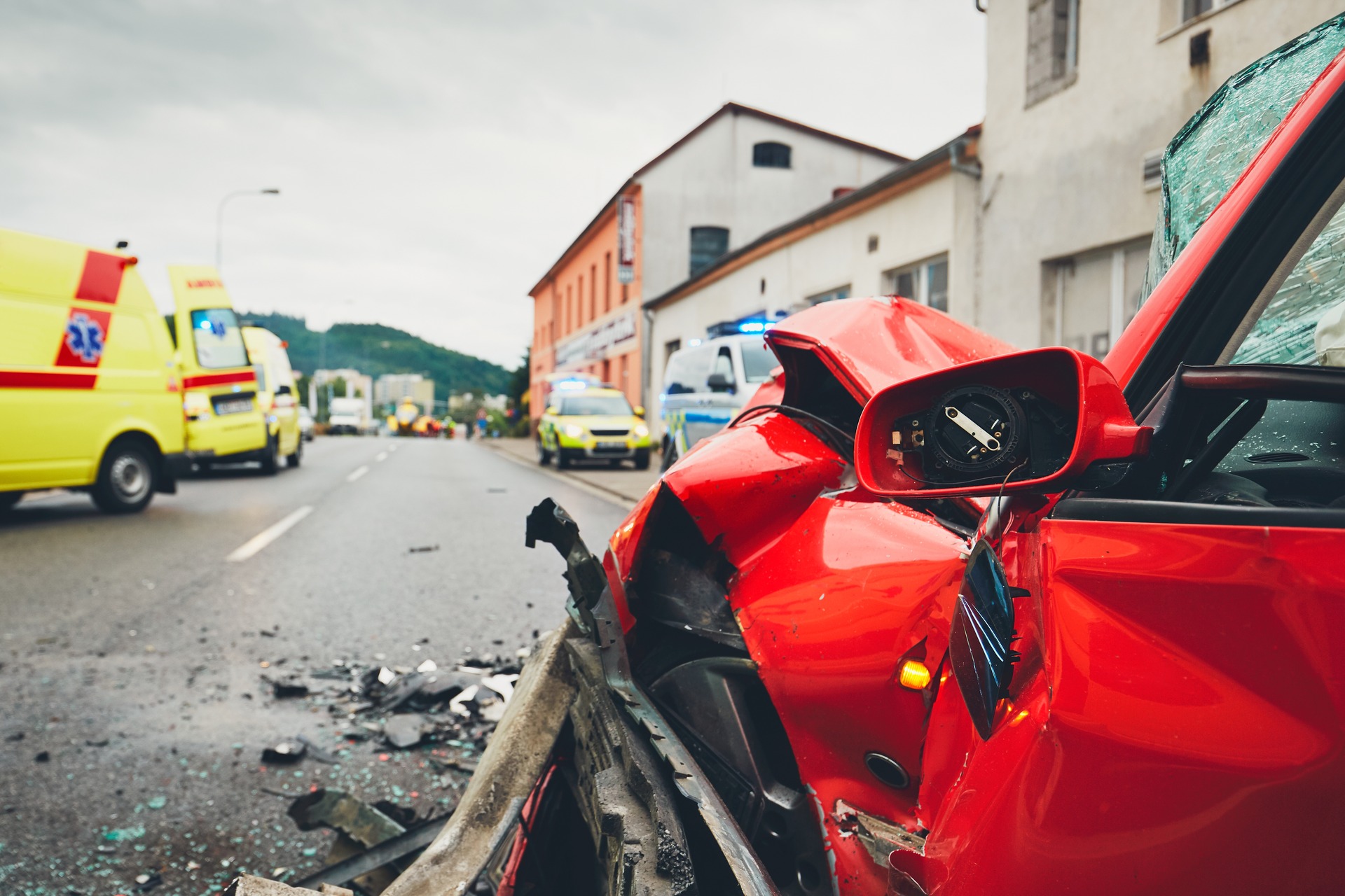 Red car wrecked with emergency vehicles on scene