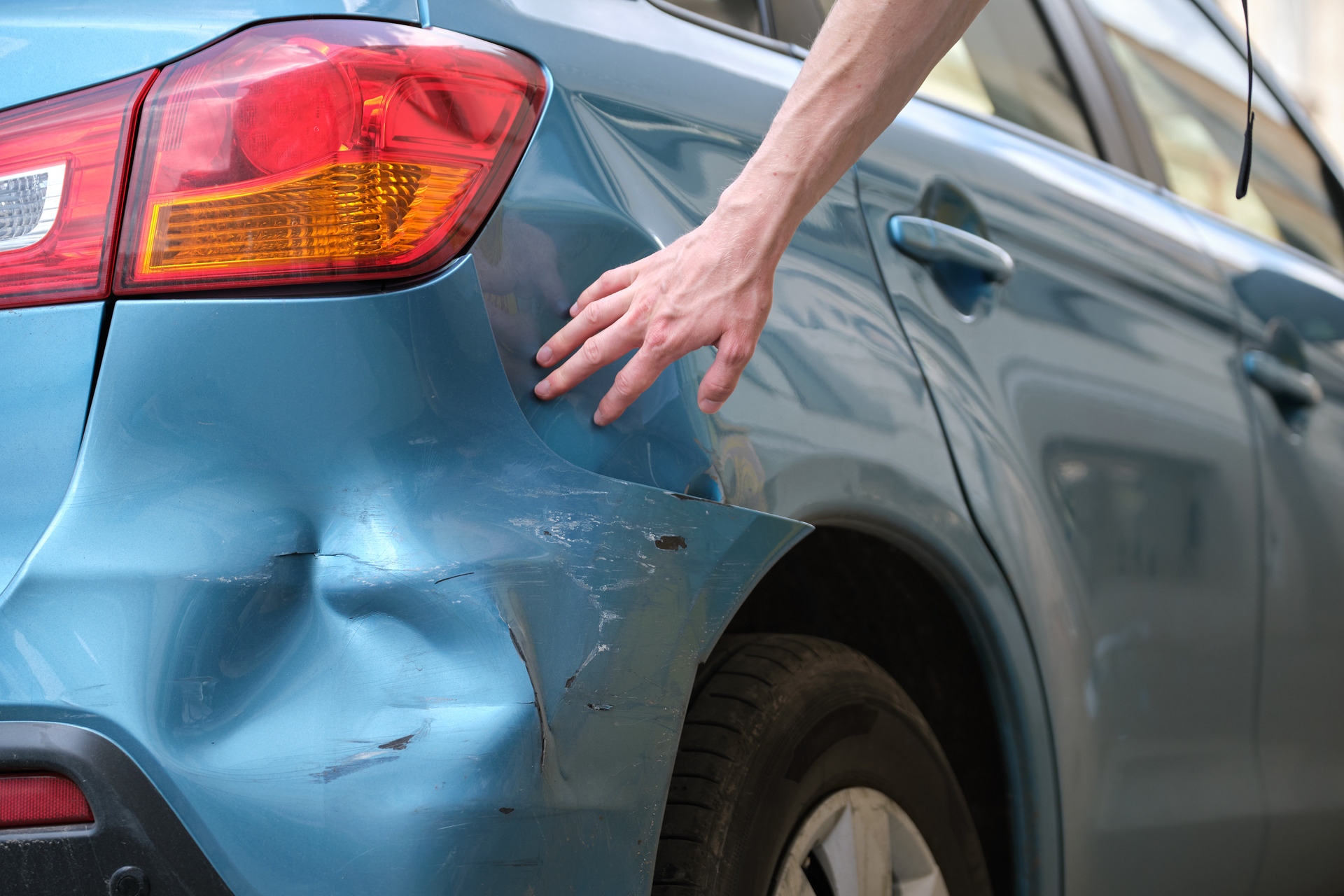 driver-hand-examining-dented-car