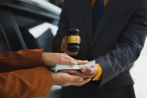A person handing over cash while a judge’s gavel is held above the transaction, symbolizing legal compensation handled with the help of a Savannah car accident lawyer.