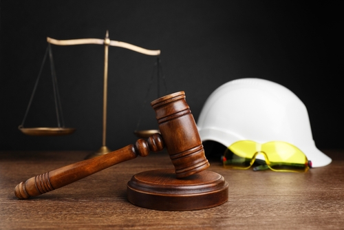 Judge’s gavel, scales of justice, and a construction hard hat on a table, symbolizing legal representation for Georgia construction accident cases.