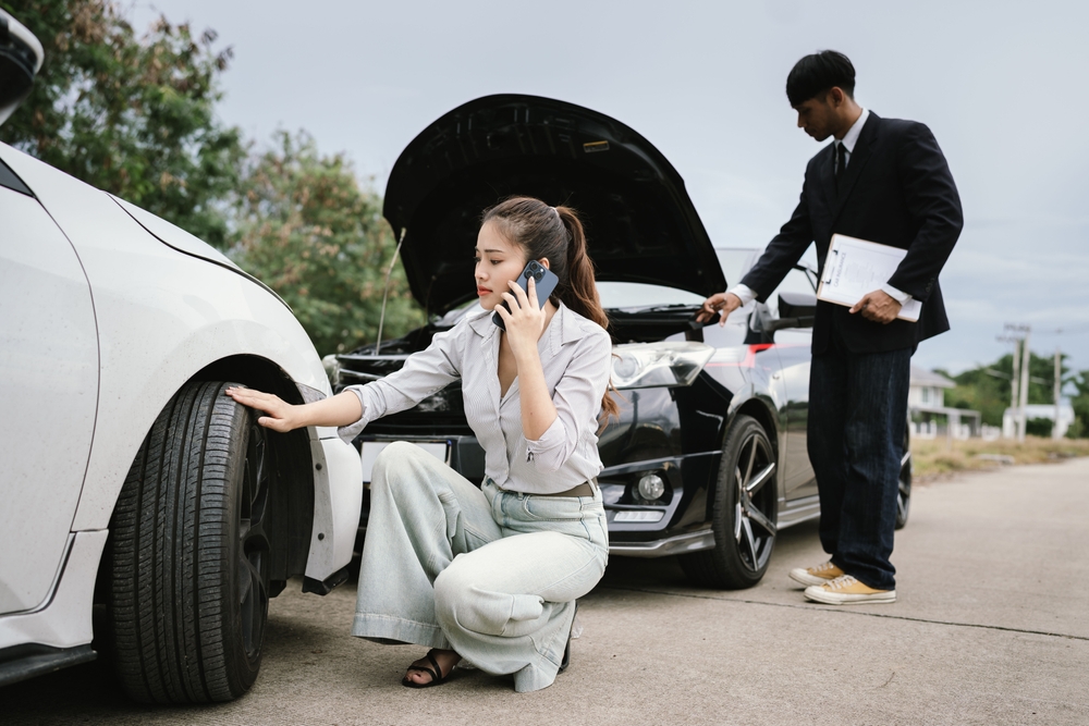 Man inspecting damaged car after crash, documenting insurance claim with mobile phone, showing frustration, analysis, and need for repair service.