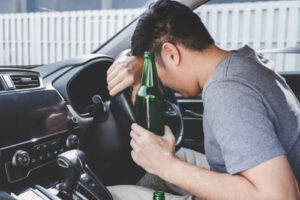 Augusta drunk driving accident lawyer representing cases involving an intoxicated driver slumped over the steering wheel holding an open bottle inside a vehicle.